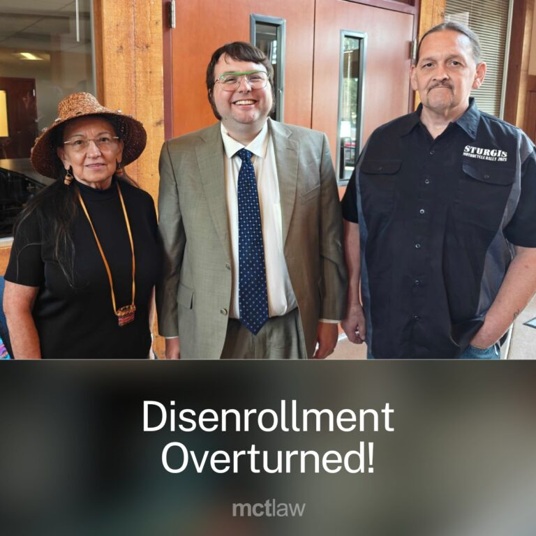 Three people standing together indoors, including a man in a suit, with overlaid text reading “Disenrollment Overturned!” and a law firm name, indicating a successful legal outcome or case victory